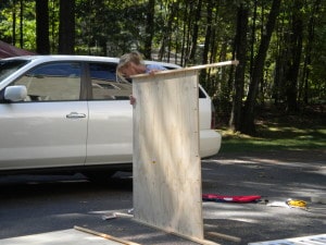 a woman holding up a piece of plywood