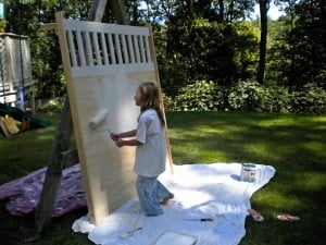 a little girl painting a pice of plywood