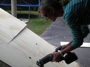 a woman cutting a large piece of plywood