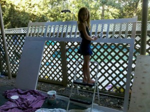 A little girl painting a bed frame white