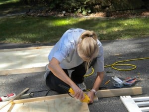 a woman drilling into wood frame