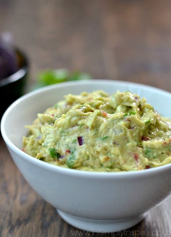 This easy Homemade Guacamole recipe is made with just a few all natural ingredients. Serve with your favorite chips or as the perfect topping on burrito bowls, chicken or fish. A close up of a bowl of Guacamole