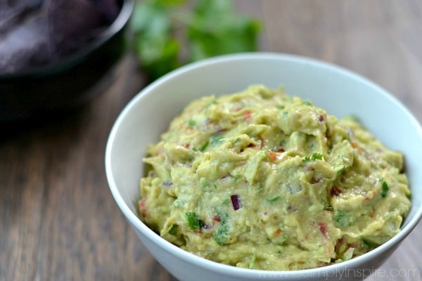 This easy Homemade Guacamole recipe is made with just a few all natural ingredients. Serve with your favorite chips or as the perfect topping on burrito bowls, chicken or fish. Homemade Guacamole recipe in a white bowl