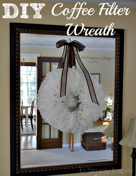 white coffee filter wreath hanging by a brown ribbon on a big mirror