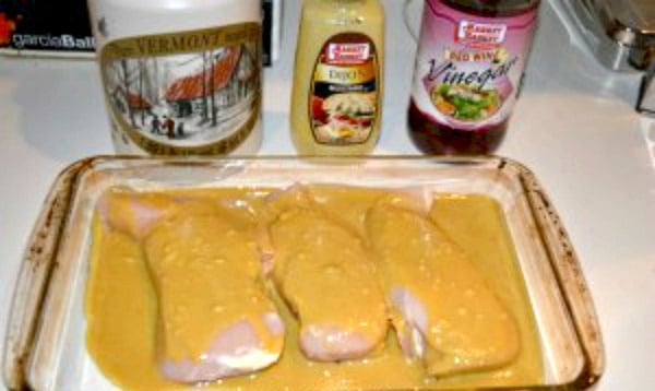 a glass dish with three chicken breasts coved in maple dijon sauce