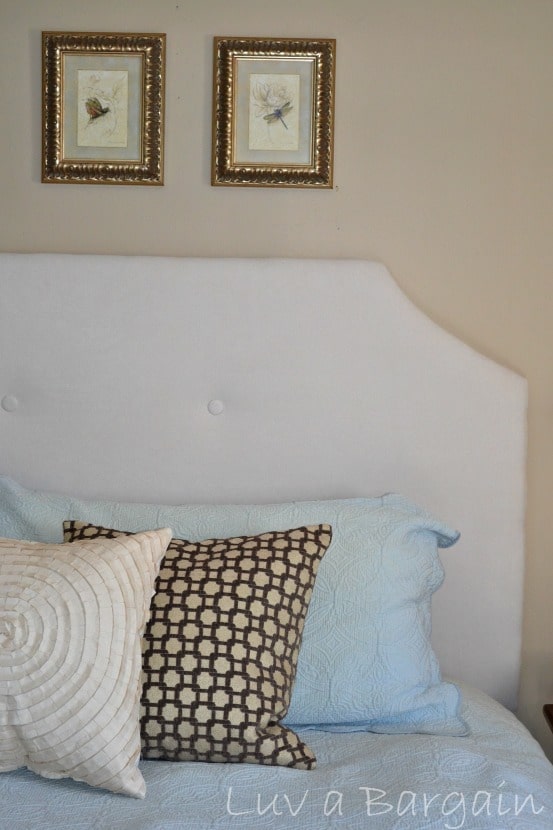 a cream upholstered headboard with blue, brown and tan pillows