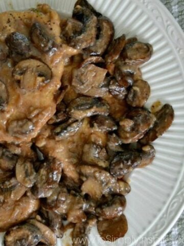 A closeup of a plate of chicken topped with cooked mushrooms