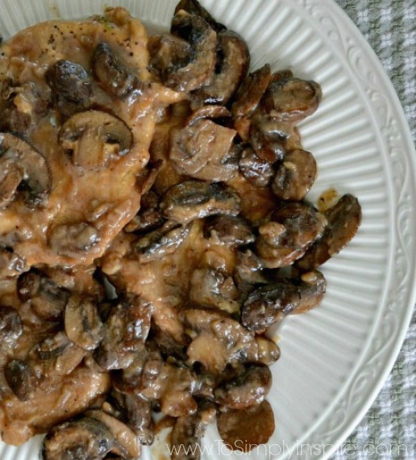 A closeup of a plate of chicken topped with cooked mushrooms