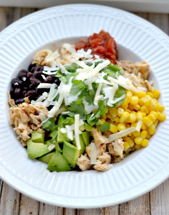 a white bowl with corn, avocado, black beans, salsa and cheese