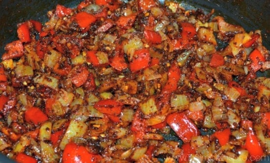 closeup of sautéing red and yellow bell pepper with chili powder