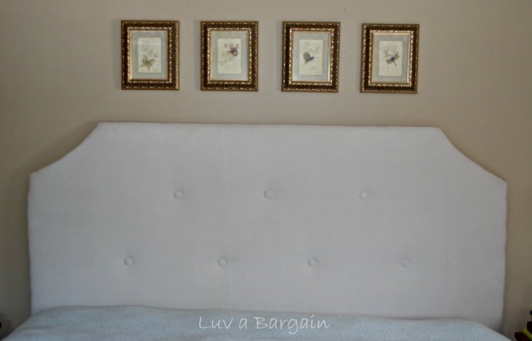a cream tufted upholstered headboard with 4 insect pictures above