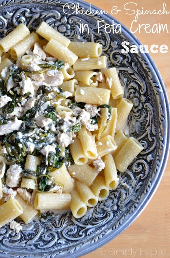 closeup of a chicken and spinach mixture over penne pasta in a silver bowl