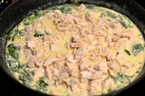 creamy chicken and spinach sauce cooking in a back skillet