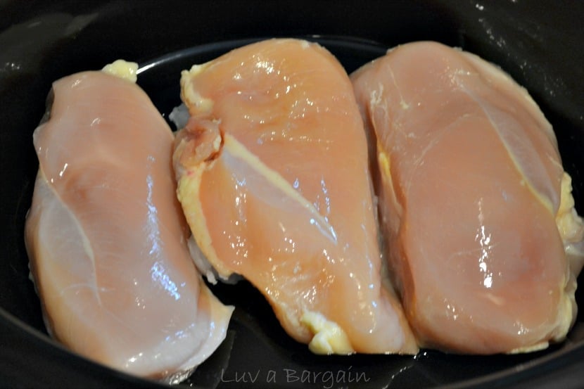 three raw chicken breasts in a black crockpot