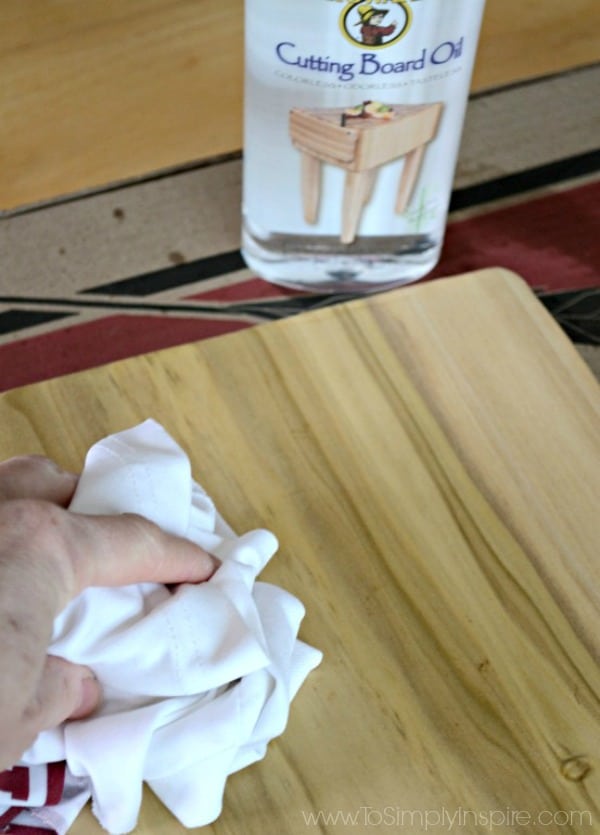 a mans hand wiping a wood cutting board with a white cloth