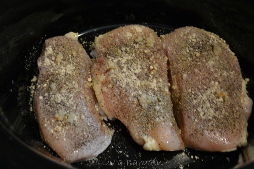 three raw chicken breast topped with spices in a black pot