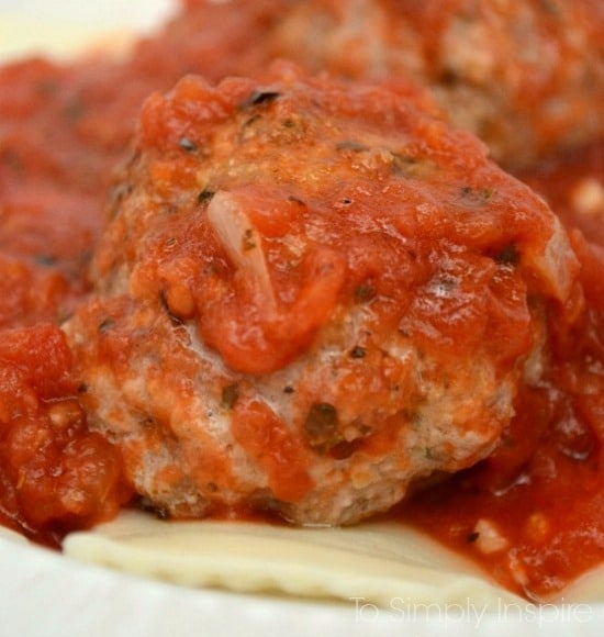 A close up of a Meatball topped with marinara sauce