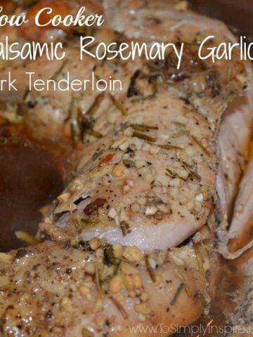 A close up of pork tenderloin in brown sauce with garlic in a slow cooker
