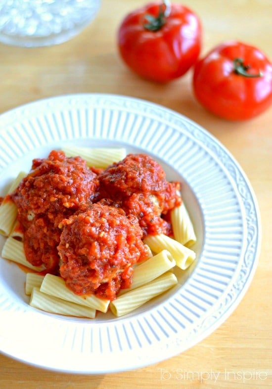 three Meatballs topped with homemade marinara sauce over penne pasta 