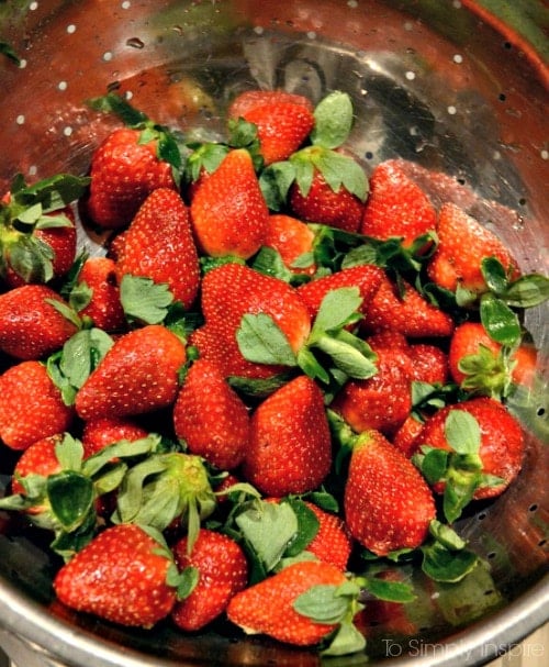 a silver strainer with fresh strawberries