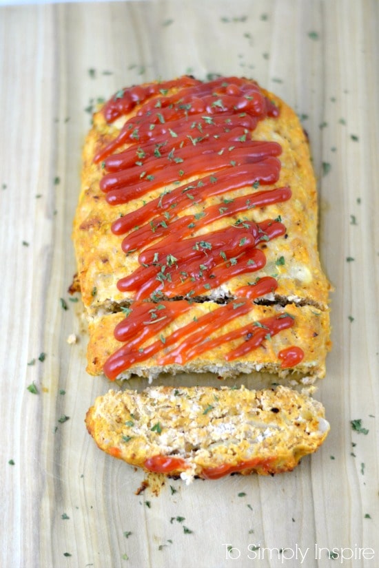 Turkey Meatloaf TTurkey Meatloaf topped with ketchup on a wood cutting board