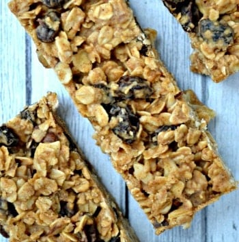three granola bars with raisins on a grey wood table