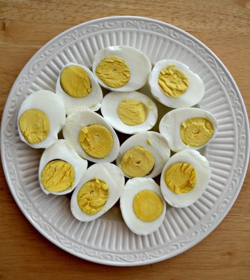 A white plate full of hard boiled eggs cut in half