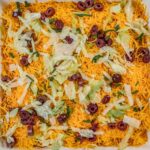 closeup of taco dip topped with shredded cheese in a rectangle glass dish