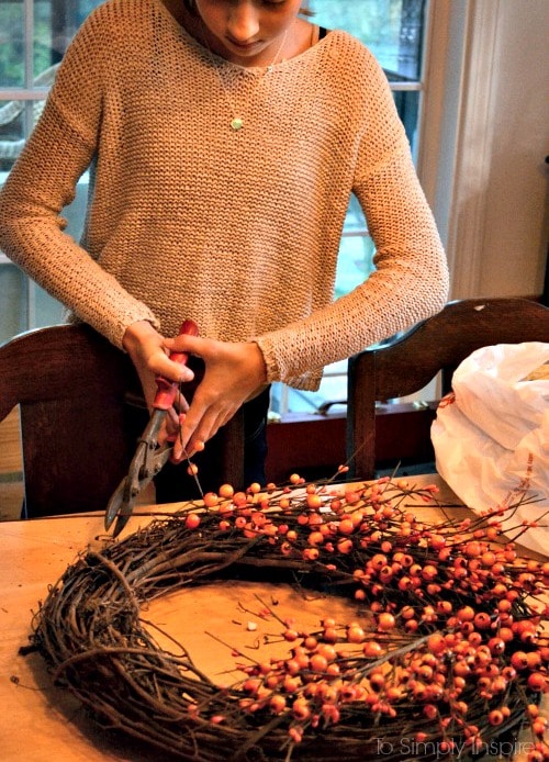 Girl cutting pieces a fall berry wreath