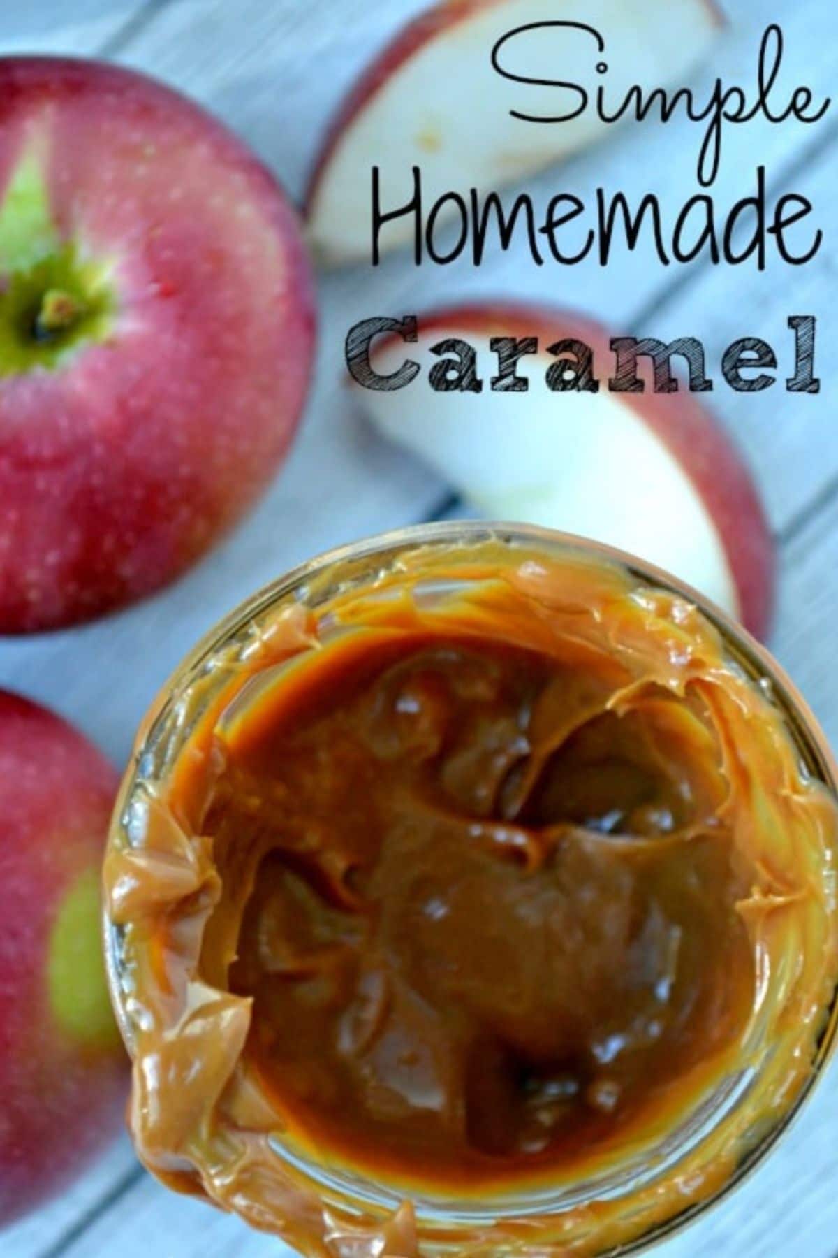 a jar with homemade caramel surrounded by red apples