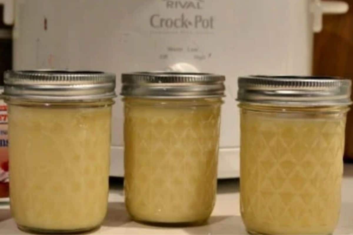 three small mason jars with condensed milk in front of a white crock pot