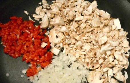 diced onions, mushrooms and red peppers in a pan