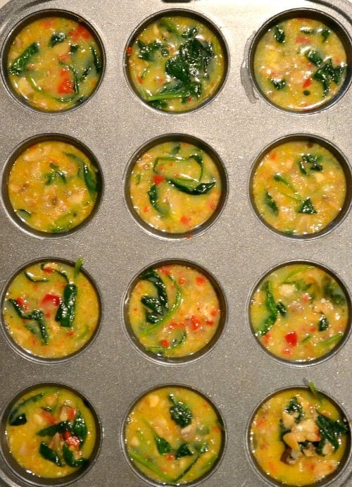 closeup of uncooked egg mixture for Spinach Quiche Muffins in a muffin tin