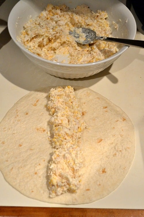 spreading chicken enchiladas mixture onto flour tortillas 