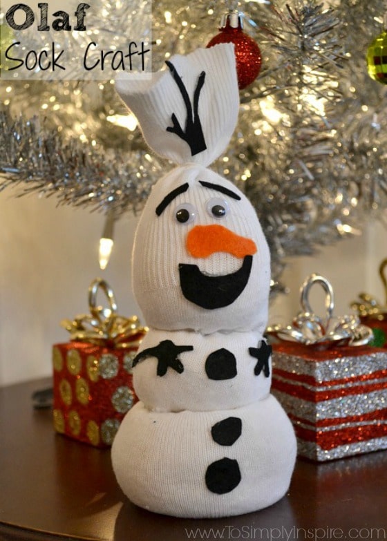 a snowman made of a white sock tied in 3 sections with orange felt nose and black felt eyes, hands and buttons