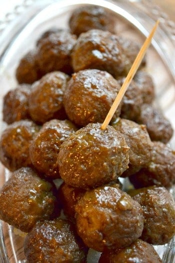 a pile of saucy meatballs on a plate with a toothpick in one
