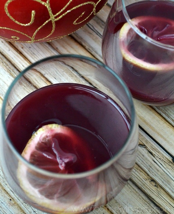 two stemless wine glass with red wine wassail and a lemon slice