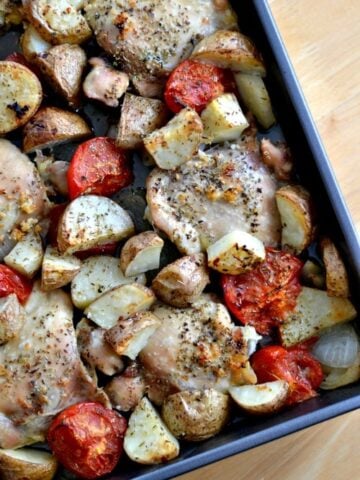 a sheet pan with roasted Chicken thighs, tomatoes, potatoes and onions
