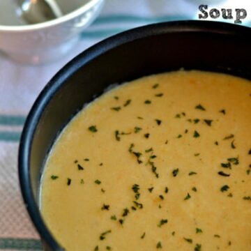 A black pot of creamy Cauliflower soup topped with parsley