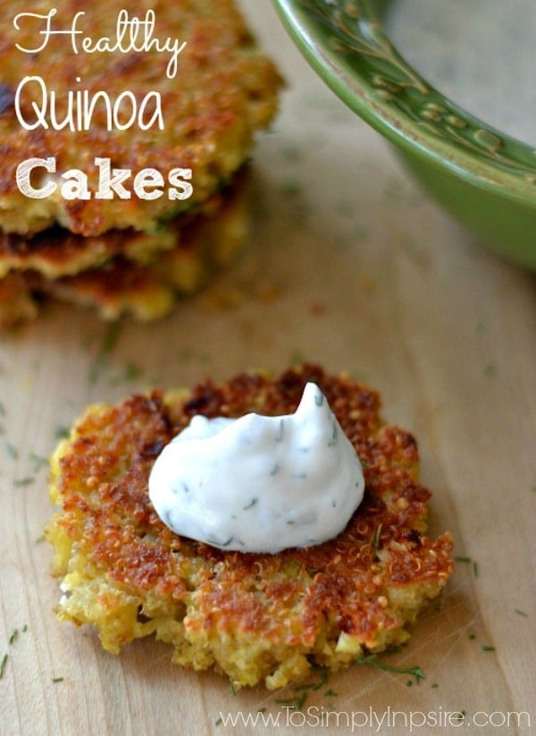 quinoa cake on a wood cutting board topped with a dollop of cucumber dill sauce