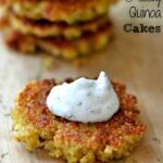quinoa cake on a wood cutting board topped with a dollop of cucumber dill sauce