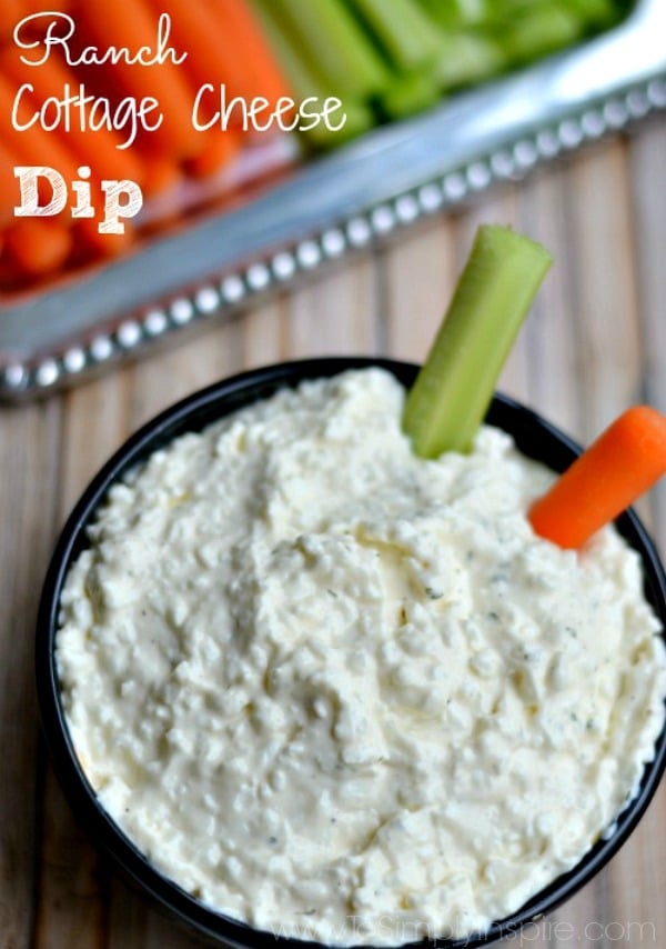 a black bowl with cottage cheese dip with a carrot and celery 