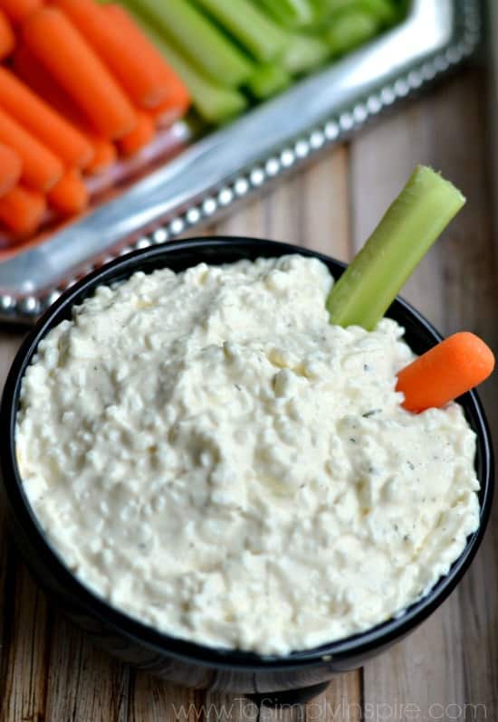 black bowl with cottage cheese dip with a carrot and celery 
