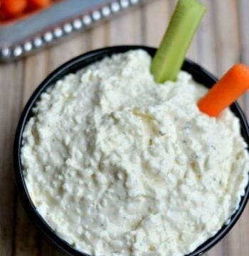 black bowl with cottage cheese dip with a carrot and celery