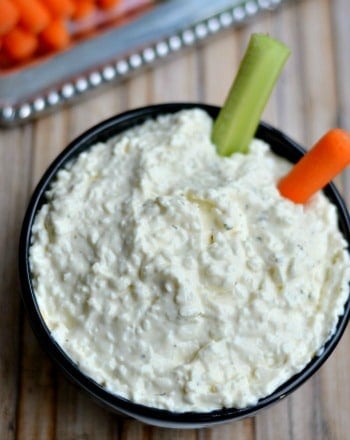 black bowl with cottage cheese dip with a carrot and celery