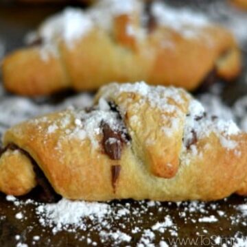 closeup of a crescent rolls covered with powdered sugar on a baking sheet