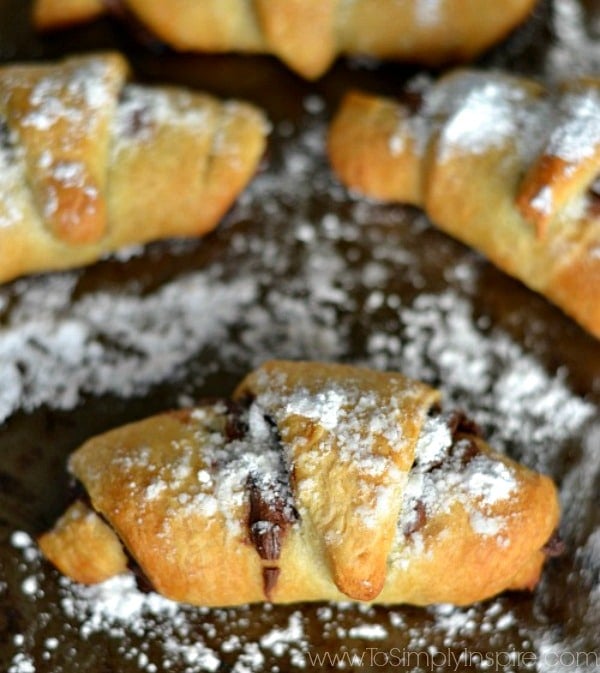 closeup of Nutella Crescent Rolls on a baking sheet sprinkled with powdered sugar.
