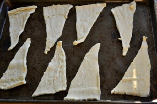 Uncooked crescent roll dough laying on a baking sheet