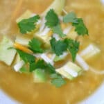 White chicken chili in a white bowl with diced avocado