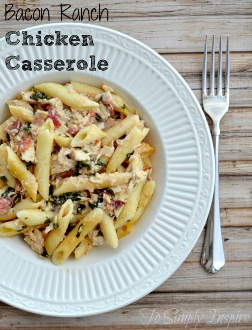 A white bowl with penne pasta with bacon, spinach and chicken